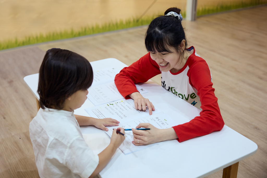 Teacher guiding student in writing individual Chinese characters